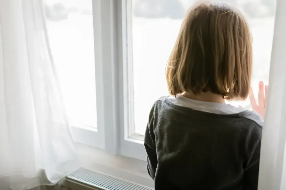Sad child girl looking out of window at home 1493247981 2125x1416 1 1166 x 777