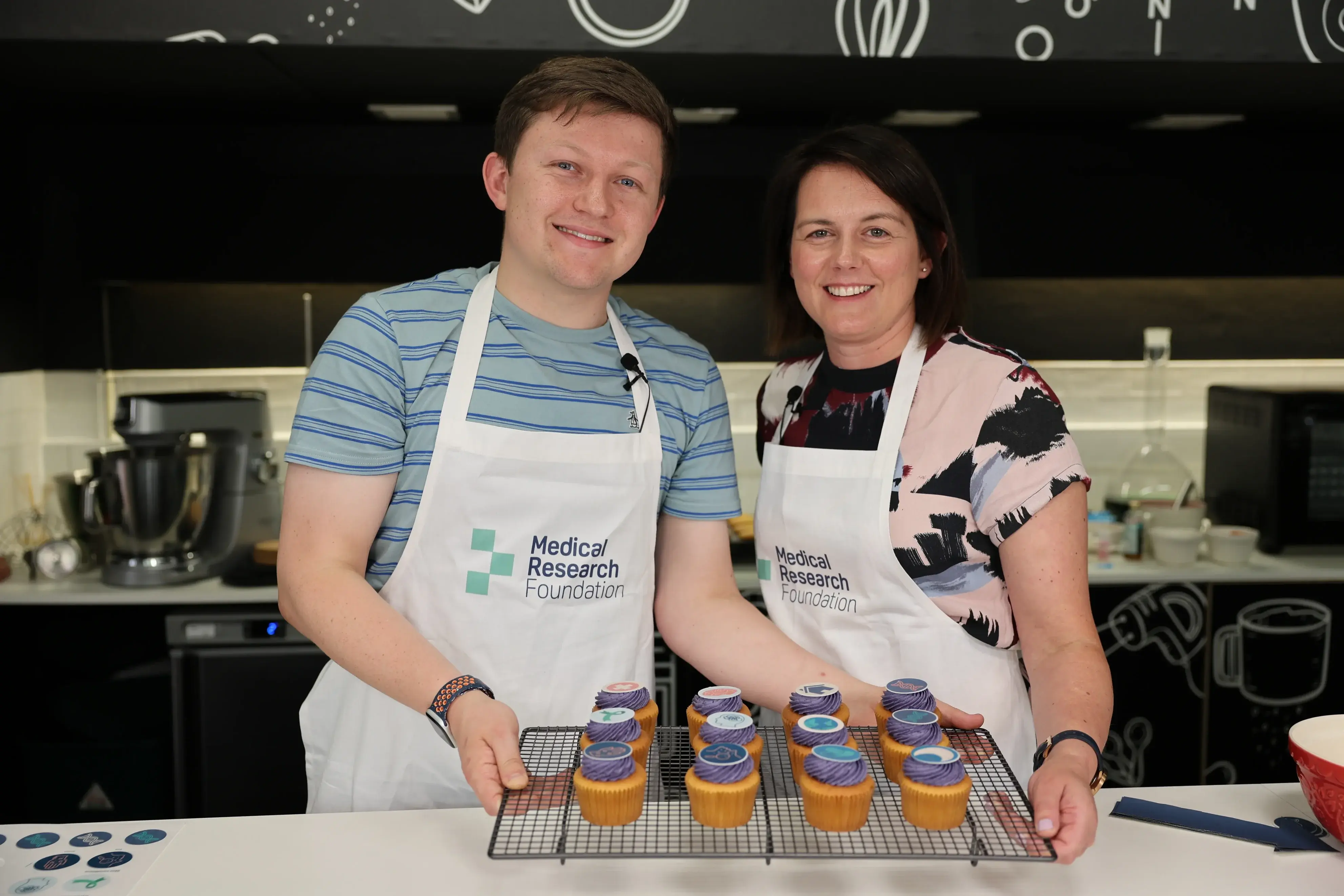 Josh Smalley and Dr Lavinia Paternoster holding a tray of science themed cupcakes